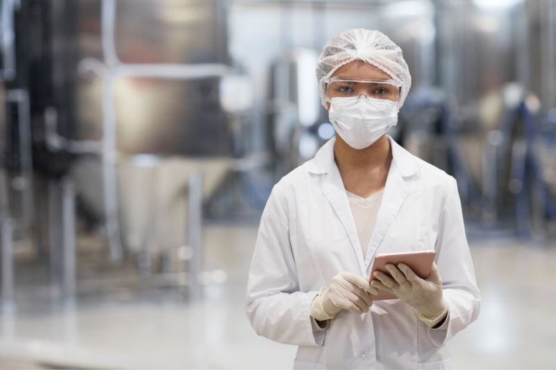 A Person In A Lab Coat And Gloves Holding A Tablet